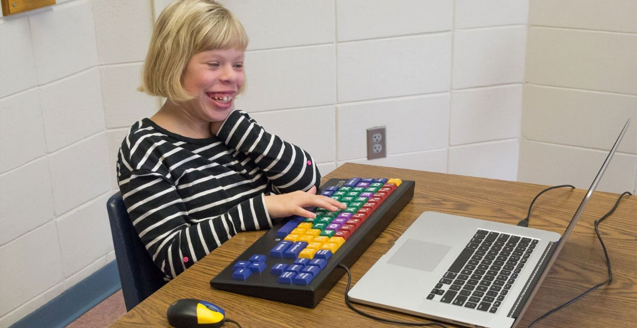 A learner is using an alternative keyboard to access a laptop.